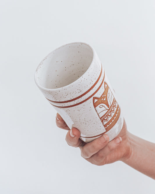 A ceramic fox-shaped tumbler with a glossy white glaze, held in a person's hand against a white background.