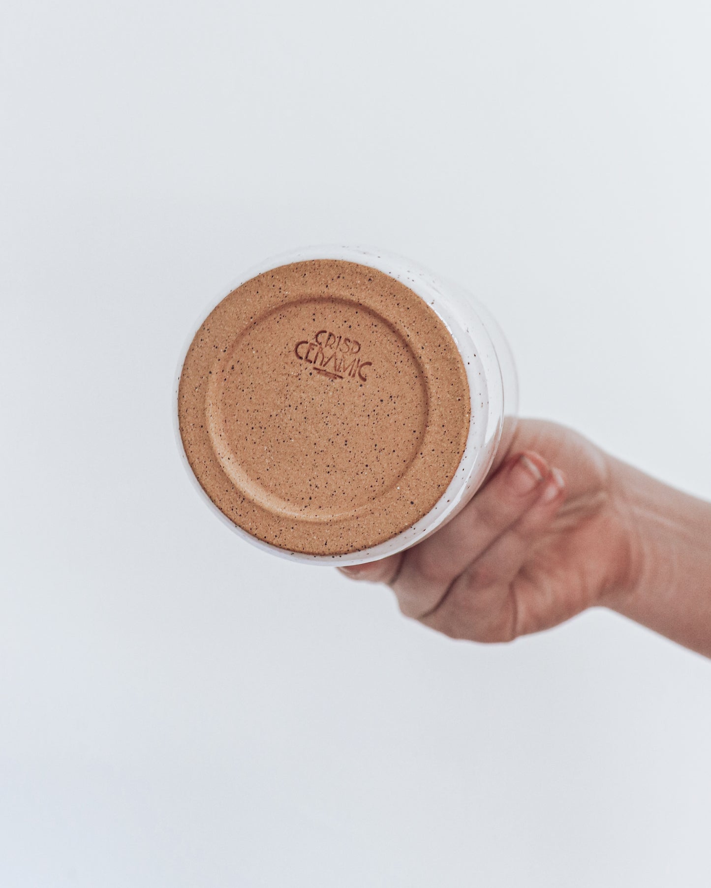 A ceramic tumbler, image shows unglazed bottom of tumbler with crisp ceramic makers mark.