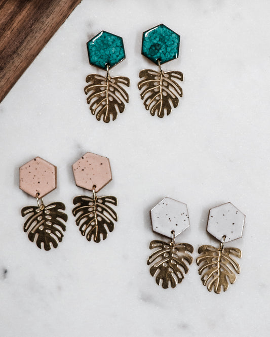 Handmade ceramic and brass monstera leaf earrings shown in three glaze colors. White, turquoise and pink