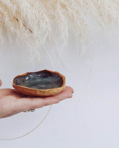 Stone Ring Dish in tide pool color glaze with raw clay edge, shown held in hand for scale.